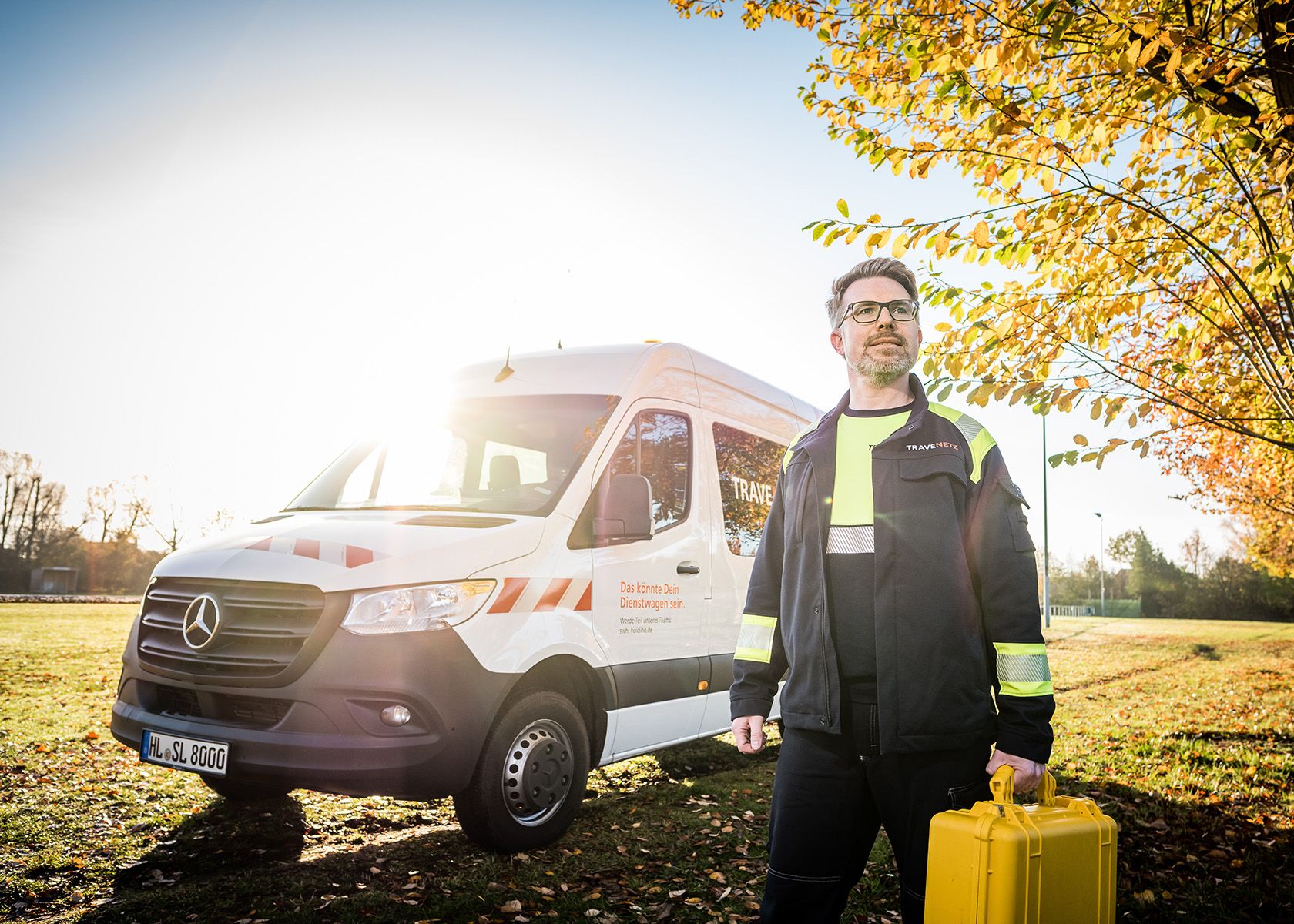 Mitarbeiter der TraveNetz mit gelbem Koffer in der Hand vor einem Service-Fahrzeug