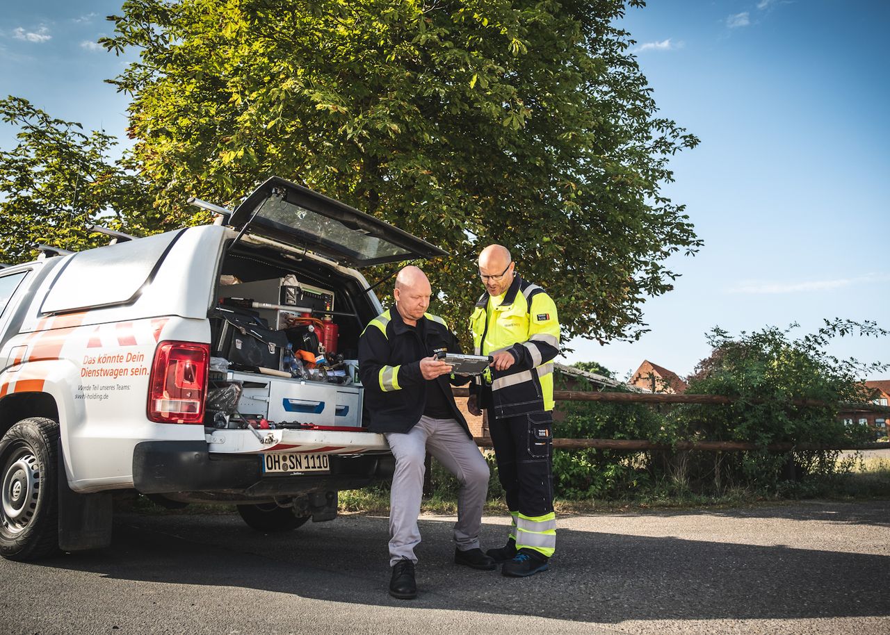 „Zwei Monteure sitzen am Auto und führen ein Gespräch